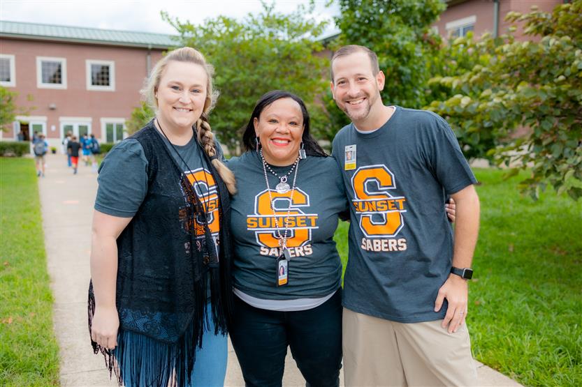 A principal and staff members smile